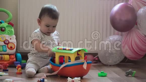婴儿学步的孩子在她生日的时候用粉红色的气球玩塑料大船视频的预览图