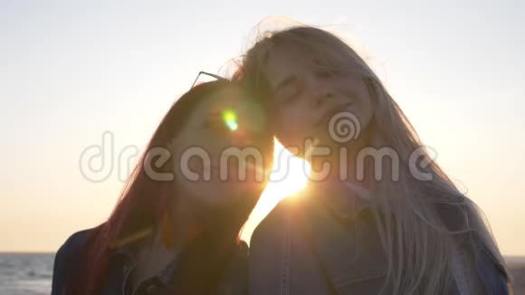 两位年轻女子头靠在海面上的肖像上面有阳光和高光视频的预览图