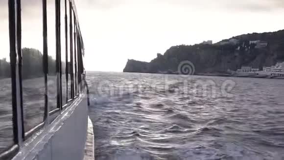 海上漂流游艇侧面观游艇在多岩石的海边滑行视频的预览图