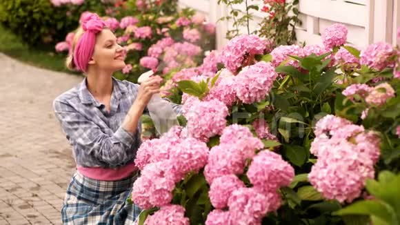漂亮的花店女喷花幸福的年轻女子在盛开的花卉植物上喷洒液体肥料花卉视频的预览图