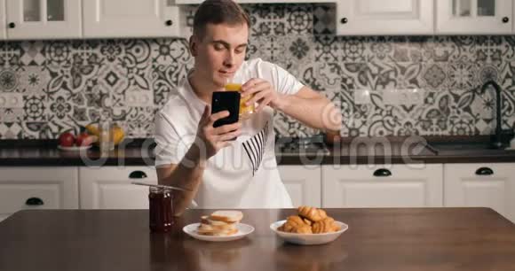 在厨房里使用智能手机的进攻性男人视频的预览图