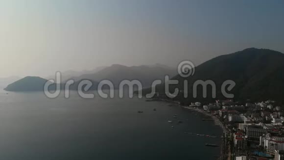 相机沿着地中海的城市海滩海岸飞行城市海滩有美丽的山脉视频的预览图