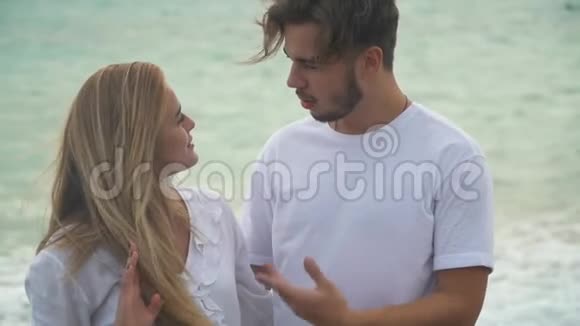 年轻夫妇在大海的背景下缓慢地交谈穿白衣服的男人和女人在海上约会视频的预览图