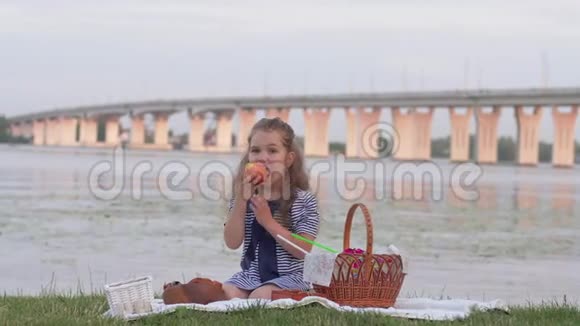 桥景河畔野餐吃新鲜水果的可爱小女孩视频的预览图