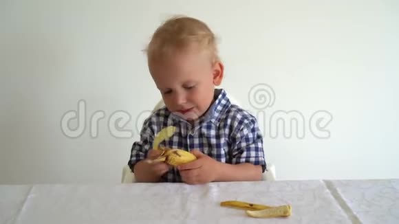 英俊的蹒跚学步的孩子正在吃黄色的香蕉关节活动度射击视频的预览图