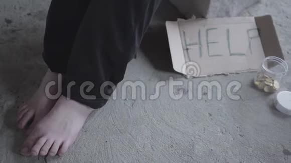 脚赤脚的可怜的女孩坐在一个尘土飞扬的空在废弃的建筑里一个标志上面写着帮助和硬币视频的预览图
