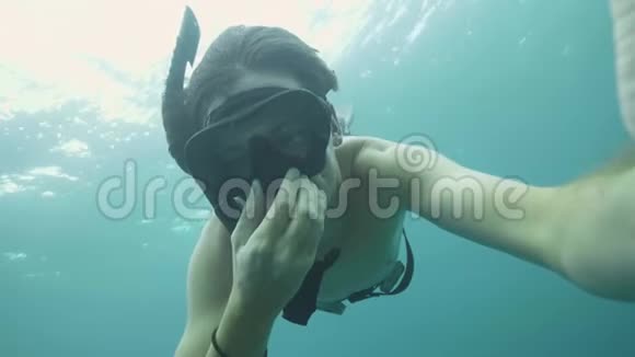 年轻的潜水员在海里潜水时吹浮潜面罩以平衡耳朵的压力拍摄自拍视频的男人视频的预览图