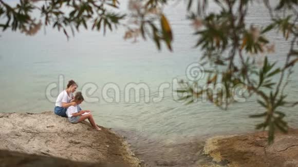 母女俩坐在海边的一块石头上聊天马蒂里日暑假视频的预览图