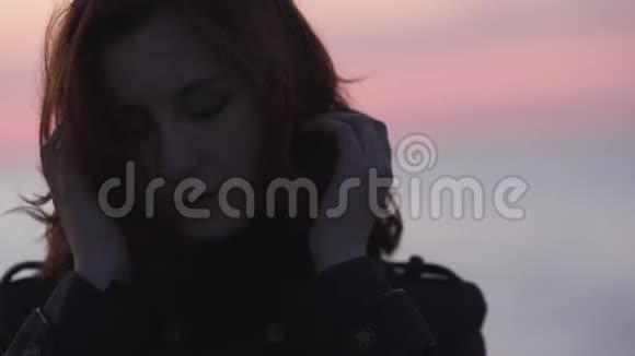 在波罗的海的一个寒冷的蓝色日落中年轻女子梦幻般的脸庞紧贴在海滩上视频的预览图