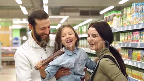 爸爸妈妈和女儿在超市的商店买香肠视频的预览图