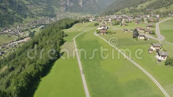 瓦莱州一个山谷中柏油路上的电子山地自行车手在阳光明媚的天气里的日景视频的预览图