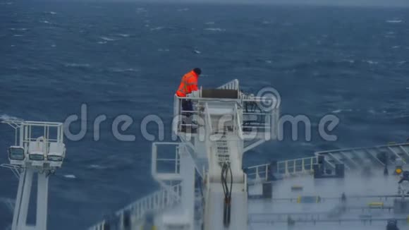 在货物起重机中的船舶上在危险条件下工作一个穿牛仔裤夹克的男人和一辆油轮上的起重机视频的预览图