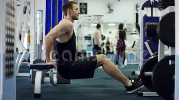 年轻运动员做俯卧撑双手背在健身房的长凳上视频的预览图