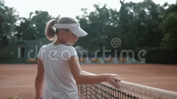 运动爱好职业青少年网球运动员用球拍接触网球网然后沿着球场走视频的预览图