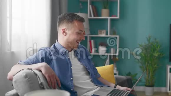 家中有魅力的男人坐沙发用笔记本电脑视频通话吗视频的预览图