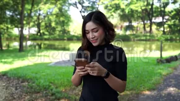 在公园里散步和使用智能手机的女人视频的预览图