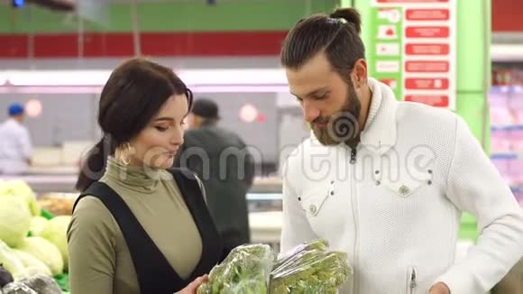 美丽的年轻微笑的夫妇一起在超市选择菜花视频的预览图