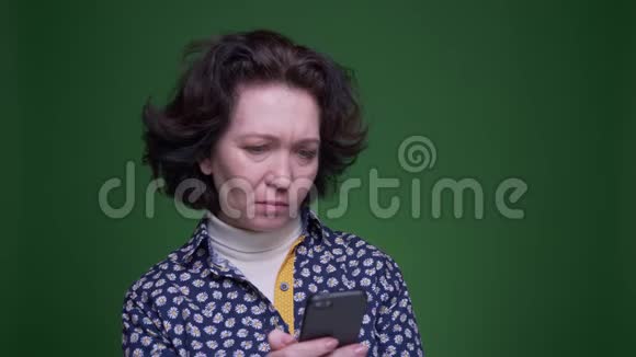 老白种人深色头发的女性用手机拍摄的特写照片背景是绿色的视频的预览图