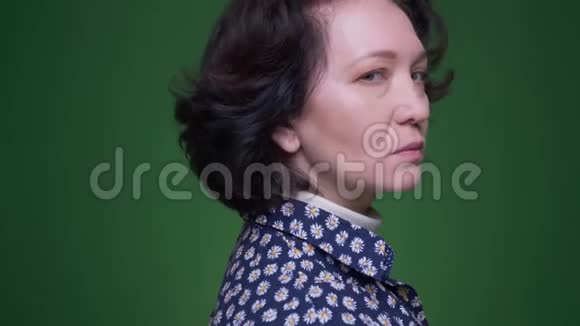 老白种人深色头发的女性近景肖像在绿色背景下拍摄的镜头视频的预览图