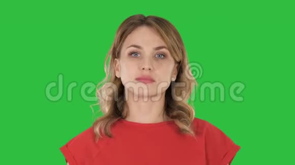 年轻女子红色t恤走着看着绿色屏幕上的相机Chroma键视频的预览图