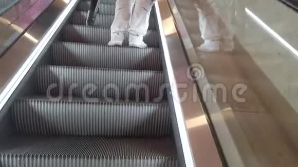 商场自动扶梯上站着的年轻男女近景视频的预览图
