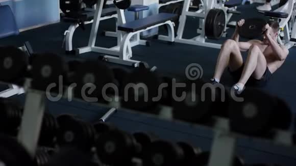 年轻运动员PU在裸露躯干的健身房里他的腹肌有额外的重量视频的预览图