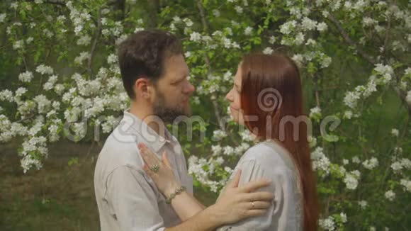 一对情侣在夏日盛开的花园里相爱一对男女的肖像视频的预览图