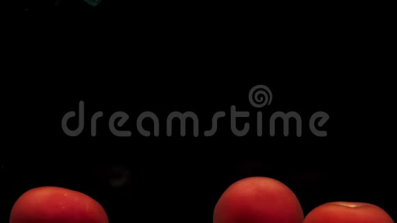 一个绿色的铲子网捕捉到一个红色的番茄并把它在透明的水中黑色的背景视频的预览图