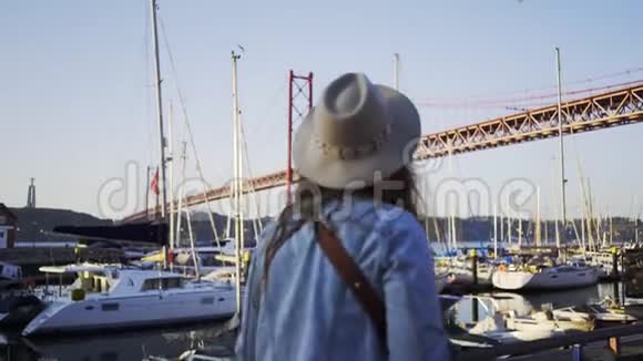 里斯本25号大桥附近的路堤上戴帽子的女孩视频的预览图