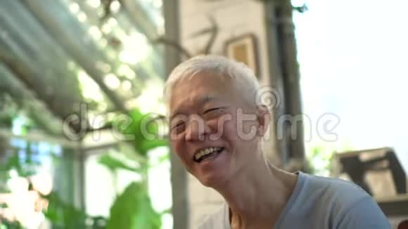 快乐的亚洲老人一边用垫子一边在咖啡馆里笑视频的预览图