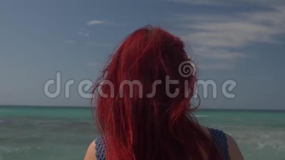 一个红头发的女人在海浪的背景下迎风飞翔的背影视频的预览图