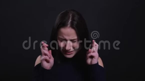 年轻漂亮的黑发女人的特写肖像她的手指交叉焦虑的背景视频的预览图