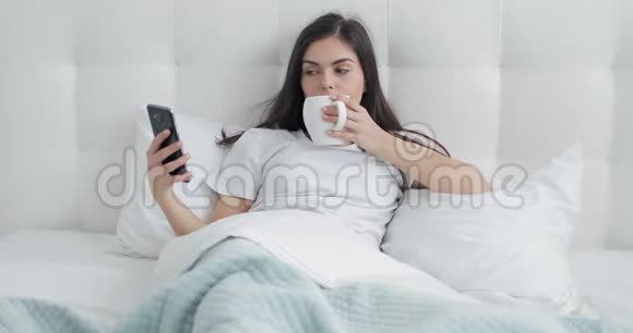 女孩在床上打电话喝咖啡视频的预览图