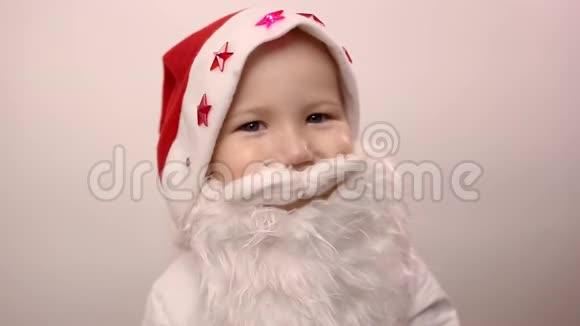 戴着圣诞老人帽子的假胡子的男孩微笑着在白色背景下笑视频的预览图