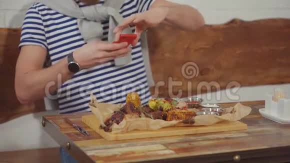 男人正在餐厅用智能手机拍摄他的晚餐特写视频的预览图