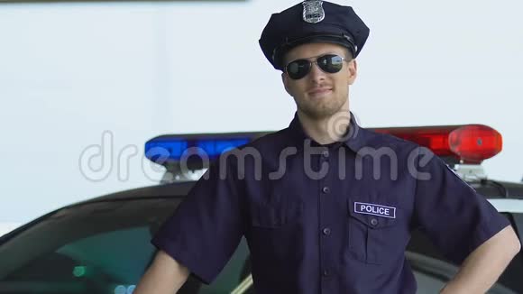 英俊的警官微笑着站在警车附近巡逻区视频的预览图