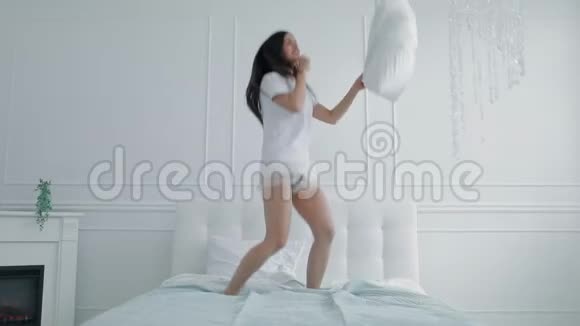 快乐的女孩在床上用枕头跳舞视频的预览图