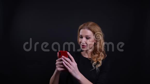 一位有魅力的红发成年女性的特写肖像她在电话中打了一个视频电话与背景愉快地交谈视频的预览图