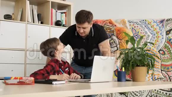 父亲看着笔记本电脑的屏幕搜索着那项重要的任务帮助他的儿子做准备视频的预览图