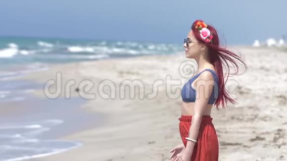 年轻女子穿着红色的裙子和蓝色的上衣红色的头发随风飘扬她的头发上戴着一个花圈视频的预览图