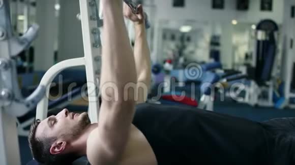 健身室里躺在长凳上锻炼杠铃的成年运动员视频的预览图