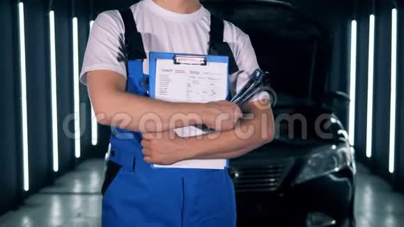 服务站和一名男性技术人员站着一个剪贴板和工具车服务汽车汽车修理理念视频的预览图