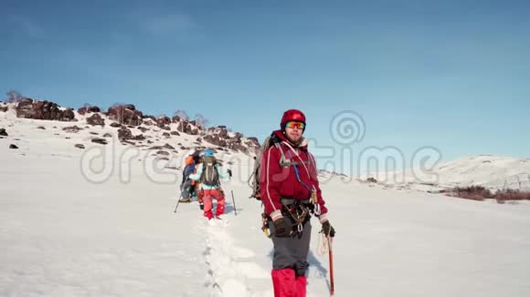 穿着红色温暖的西装站在雪地里手里拿着冰镐望着远处在他身后视频的预览图