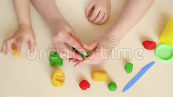 妈妈和孩子谁玩塑料面团混合模型特写手顶部视图视频的预览图