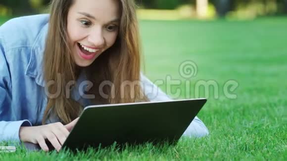 公园里的笔记本电脑上有好消息的快乐女人视频的预览图
