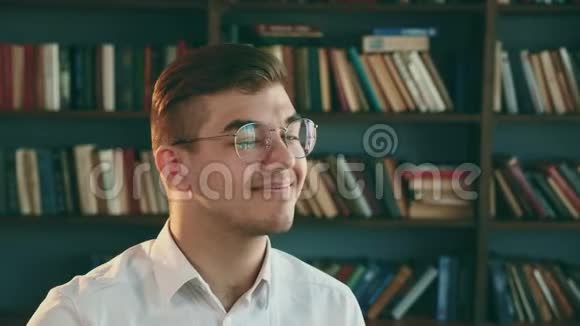 带着眼镜的年轻人微笑着看着相机图书馆学生视频的预览图