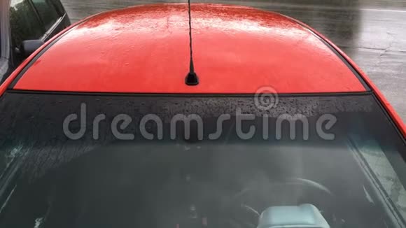 雨滴和雨滴滴在停着的红色客车的挡风玻璃和车顶上秋天多雨的天气特写视频的预览图