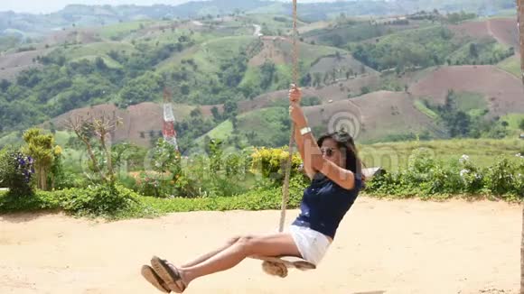 在泰国的风电场一个女人拿着绳子摇椅快乐地玩着背景山视频的预览图