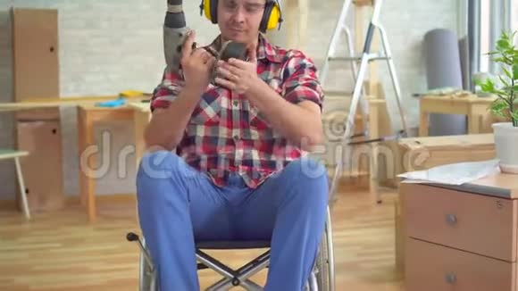 一位戴着头盔手里拿着电钻坐在轮椅上的残疾青年画像视频的预览图