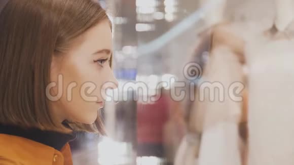 商店橱窗里年轻漂亮的女人她的脸映在橱窗里视频的预览图